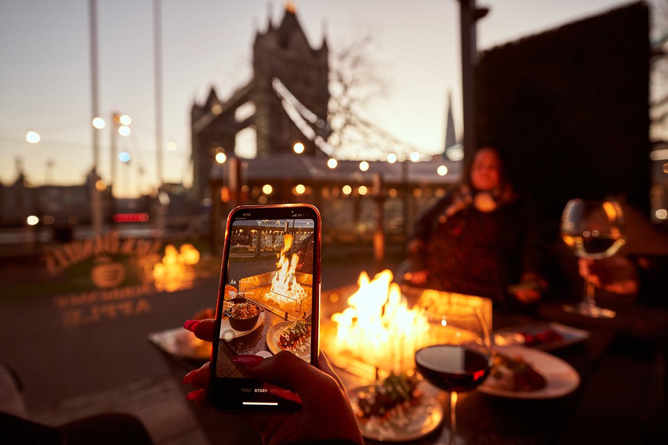 A couple in front of a fire pit taking a photo